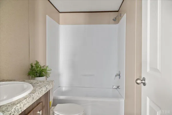 a bathroom with a granite countertop bathtub shower sink and toilet