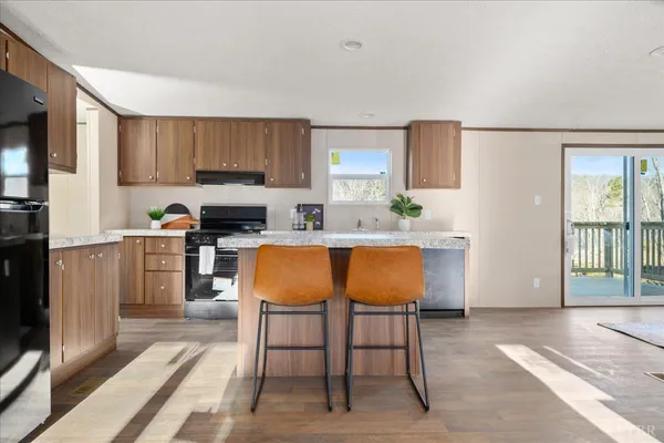a kitchen with stainless steel appliances kitchen island granite countertop a table chairs sink and cabinets