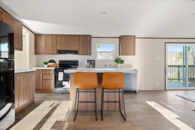 a kitchen with stainless steel appliances kitchen island granite countertop a table chairs sink and cabinets