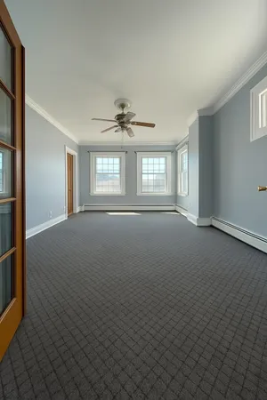 an empty room with windows and chandelier fan