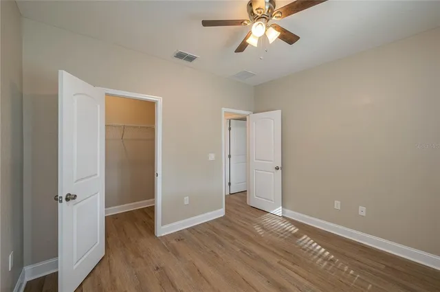 an empty room with wooden floor closet and windows