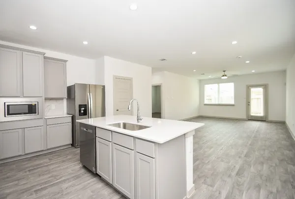 a kitchen with a sink a refrigerator and white cabinets