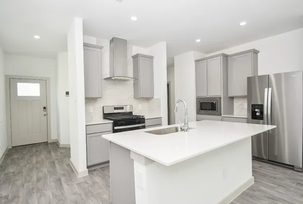 a kitchen with stainless steel appliances a stove a refrigerator white cabinets and wooden floor