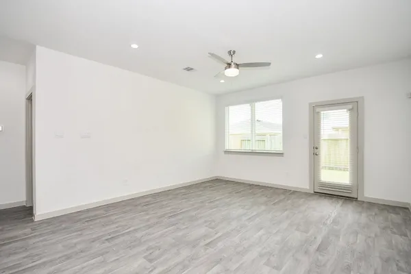 an empty room with wooden floor fan and windows