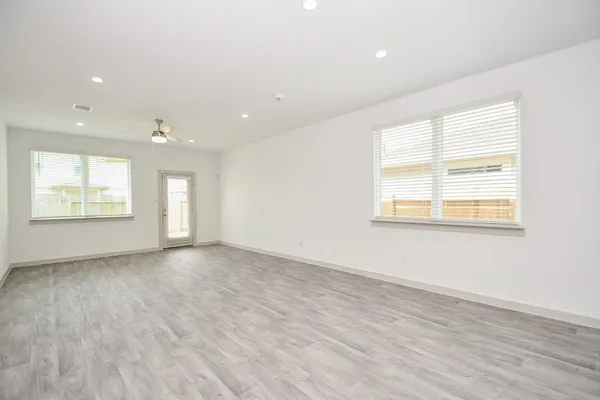 an empty room with wooden floor and windows