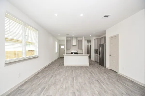 a large white kitchen with kitchen island a sink wooden floor and a large window
