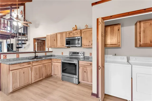 a kitchen with stainless steel appliances granite countertop a refrigerator oven a sink dishwasher and wooden cabinets with wooden floor