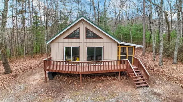 a view of a small house with a yard deck and furniture