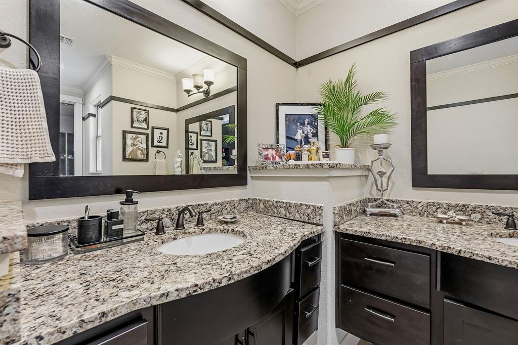 15317 Falconhead Grove Loop Austin, TX 78738 - Photo 15 of 29 Elegant primary bath featuring dark wood vanities and speckled granite countertops with dual sinks.