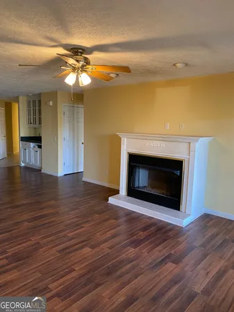 a view of an empty room with wooden floor and a fireplace