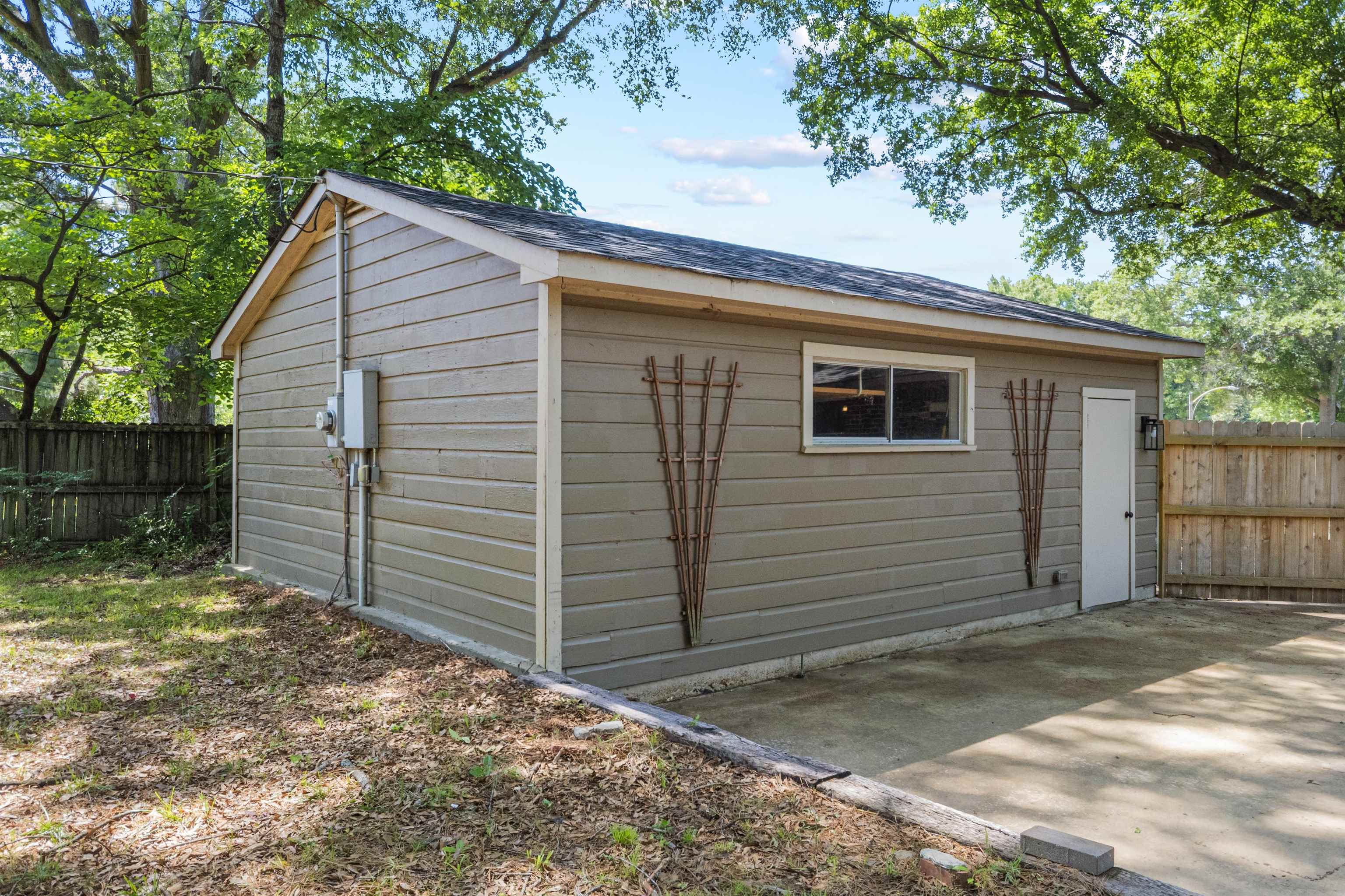 5271 Princeton Road Memphis, TN 38120 - Photo 8 of 30 Detached accessory building featuring horizontal siding, a single window, a side entry door with an exterior light fixture, and a gravel pad