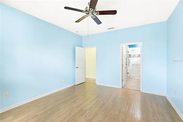 an empty room with wooden floor ceiling fan and windows