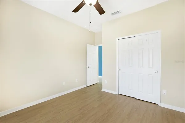 an empty room with ceiling fan and window