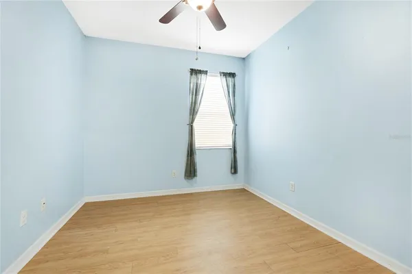 an empty room with a window and a ceiling fan