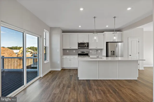 a kitchen with stainless steel appliances granite countertop a refrigerator a sink dishwasher a stove and white cabinets with wooden floor