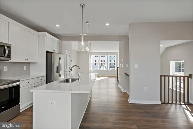 a kitchen with stainless steel appliances a refrigerator a sink dishwasher a oven with white cabinets and wooden floor