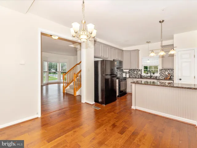 a view of a kitchen with stainless steel appliances granite countertop a refrigerator a oven a stove and a wooden floors