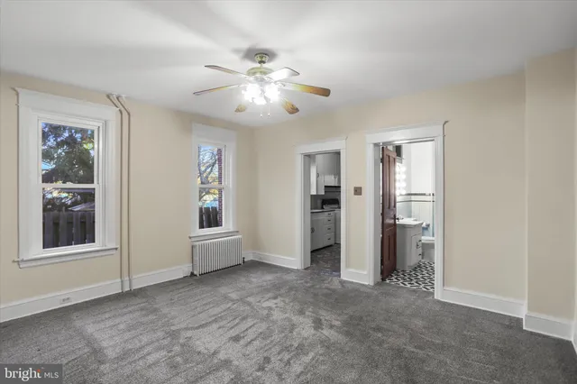 an empty room with chandelier fan and windows