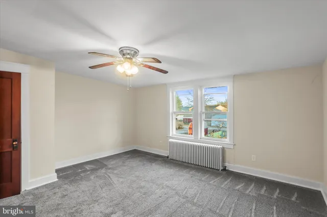 an empty room with chandelier fan and windows