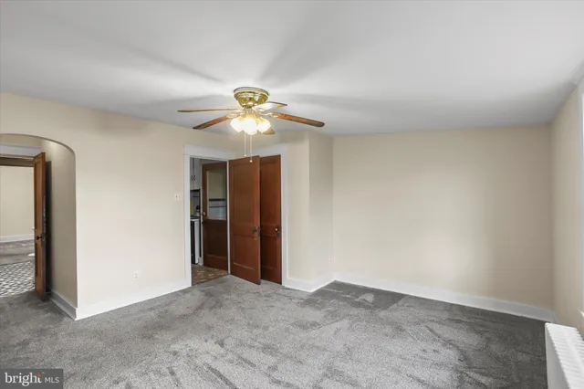 an empty room with closet and a chandelier fan