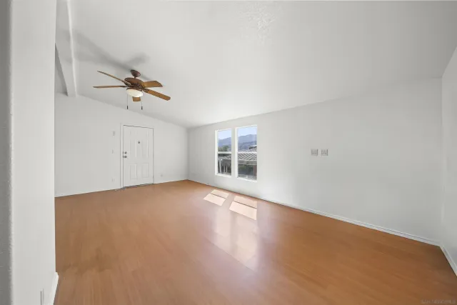 an empty room with a wooden floor and windows
