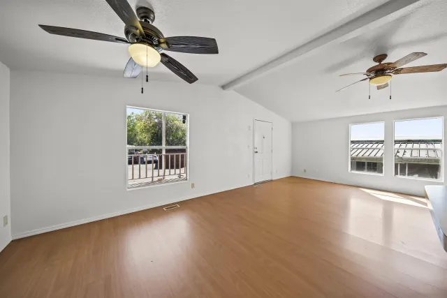 a view of an empty room with a window and wooden floor
