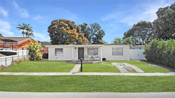 a view of a house with a big yard and a large trees