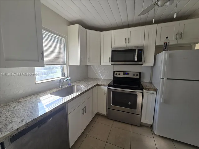 a kitchen with granite countertop white cabinets white stainless steel appliances and a sink