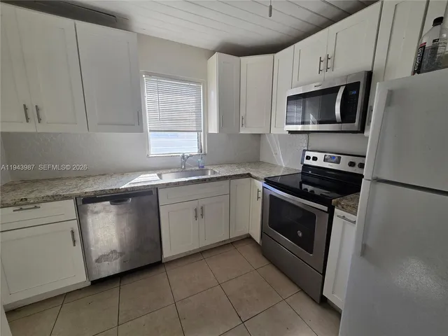 a kitchen with granite countertop white cabinets stainless steel appliances and a sink