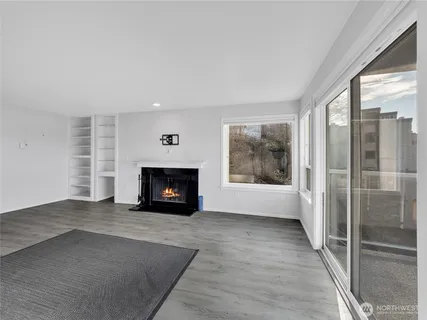 an empty room with fireplace wooden floor and windows