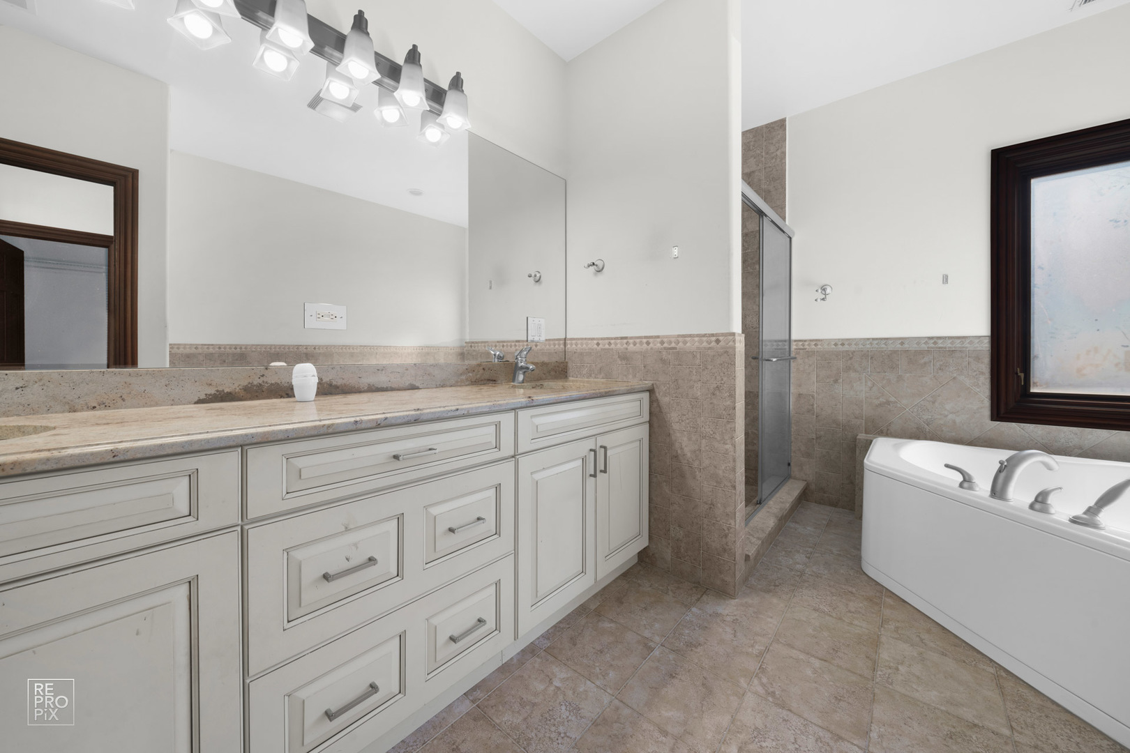 916 Elmdale Road Glenview, IL 60025 - Photo 15 of 20 a spacious bathroom with a granite countertop sink a bathtub a mirror and vanity