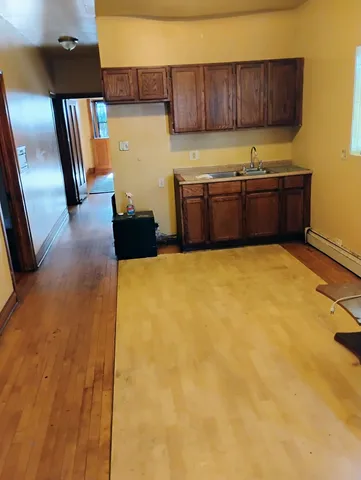 a view of a kitchen with refrigerator and wooden floor