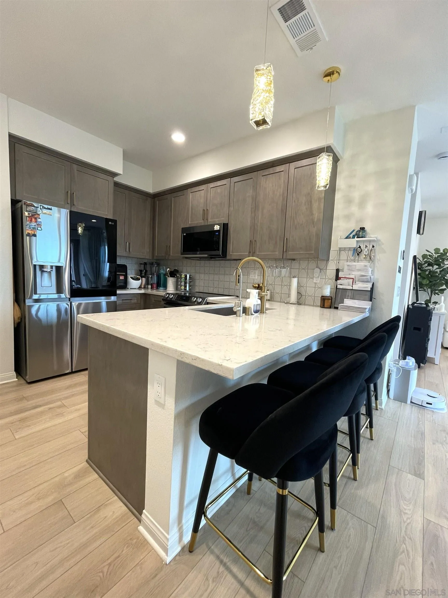 2708 Juniper Berry Street Spring Valley, CA 91977 - Photo 27 of 39 a kitchen with stainless steel appliances kitchen island granite countertop a table chairs sink and cabinets