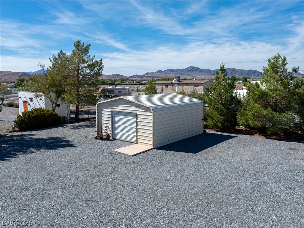 4080 Magnet Road Pahrump, NV 89048 - Photo 25 of 28 Detached metal outbuilding sits on a spacious gravel lot framed by distant mountain views.