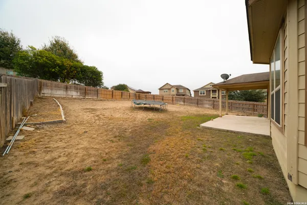 a view of a swimming pool with a yard and wooden fence