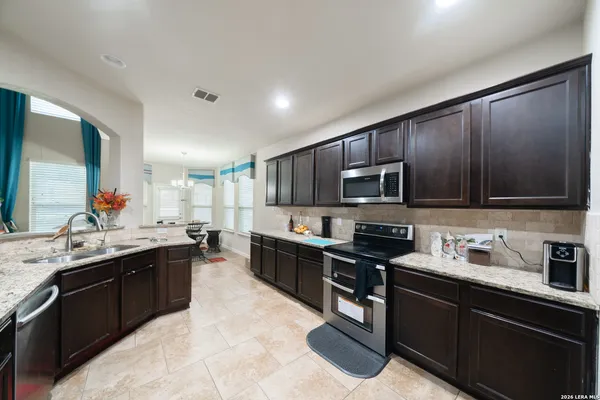 a kitchen with stainless steel appliances granite countertop wooden cabinets a stove top oven a sink and dishwasher