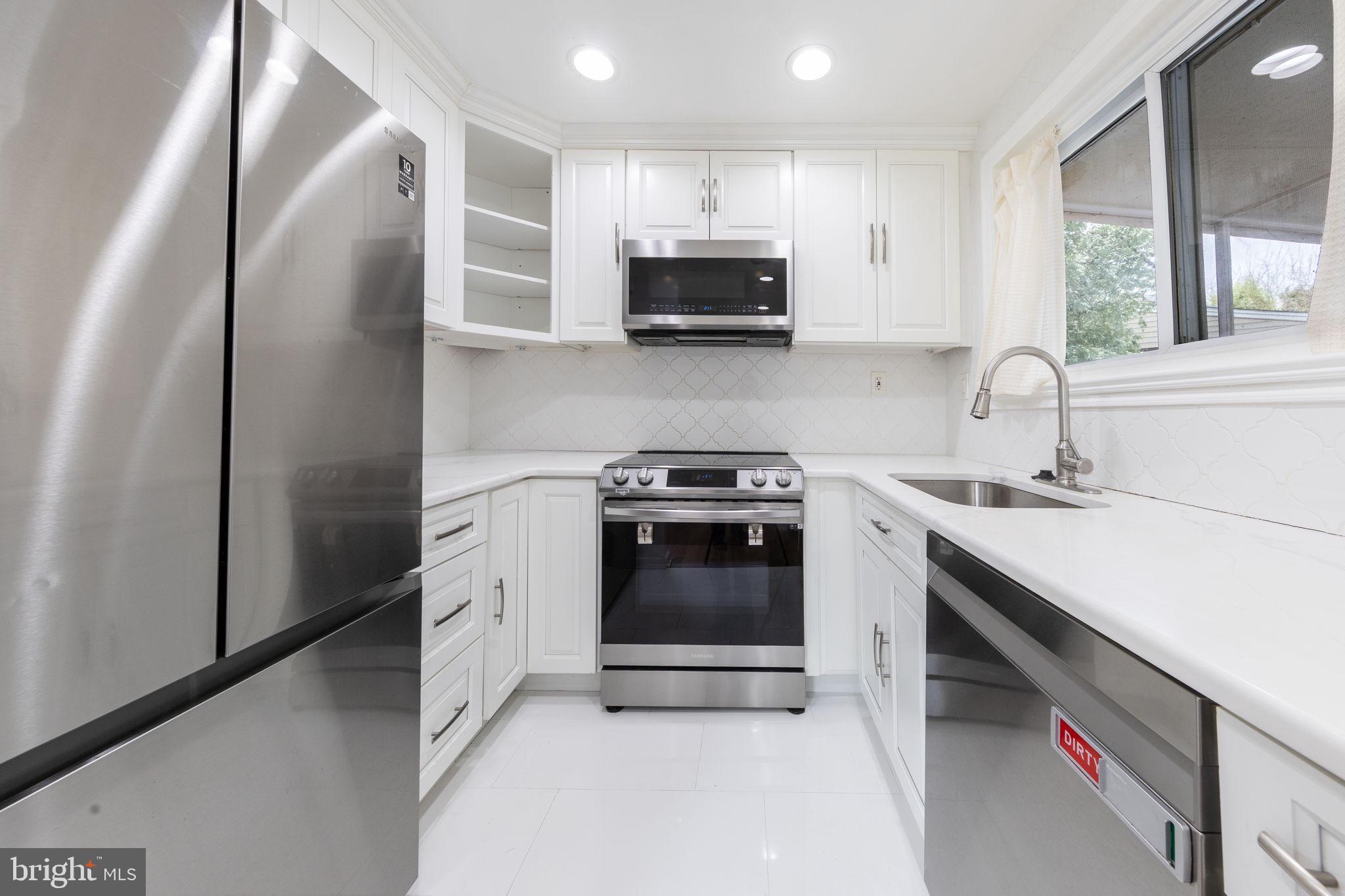12112 Atherton Drive Silver Spring, MD 20902 - Photo 7 of 32 a kitchen with stainless steel appliances a stove microwave and sink