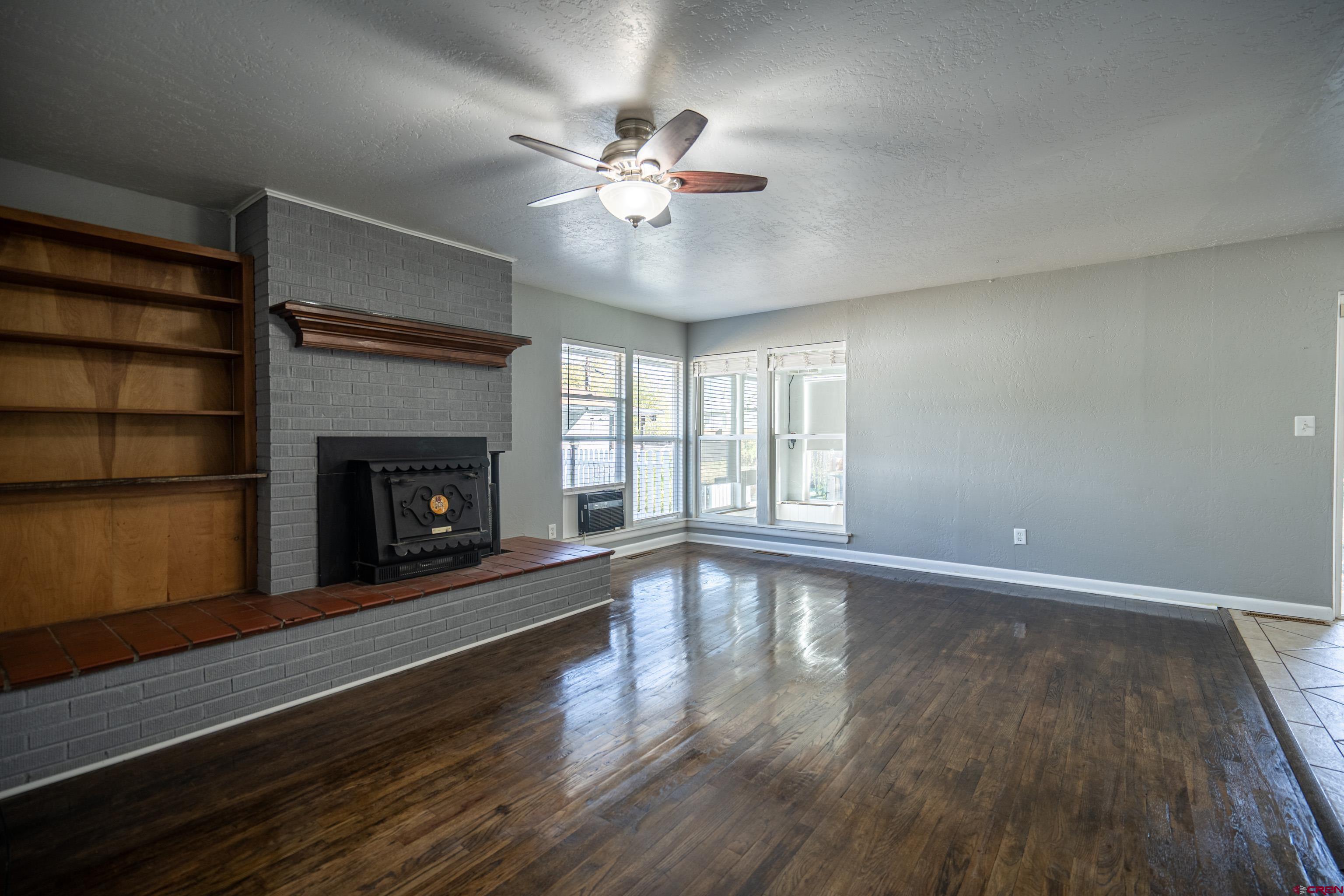 1702 East MacArthur Avenue Cortez, CO 81321 - Photo 4 of 42 a view of an empty room with wooden floor fireplace and a window