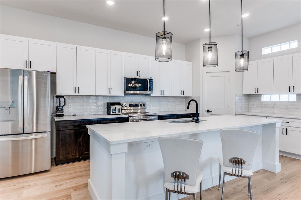 2134 Shea Road, Unit 1001 Dallas, TX 75235 - Photo 6 of 12 a kitchen with stainless steel appliances kitchen island a refrigerator and a stove top oven