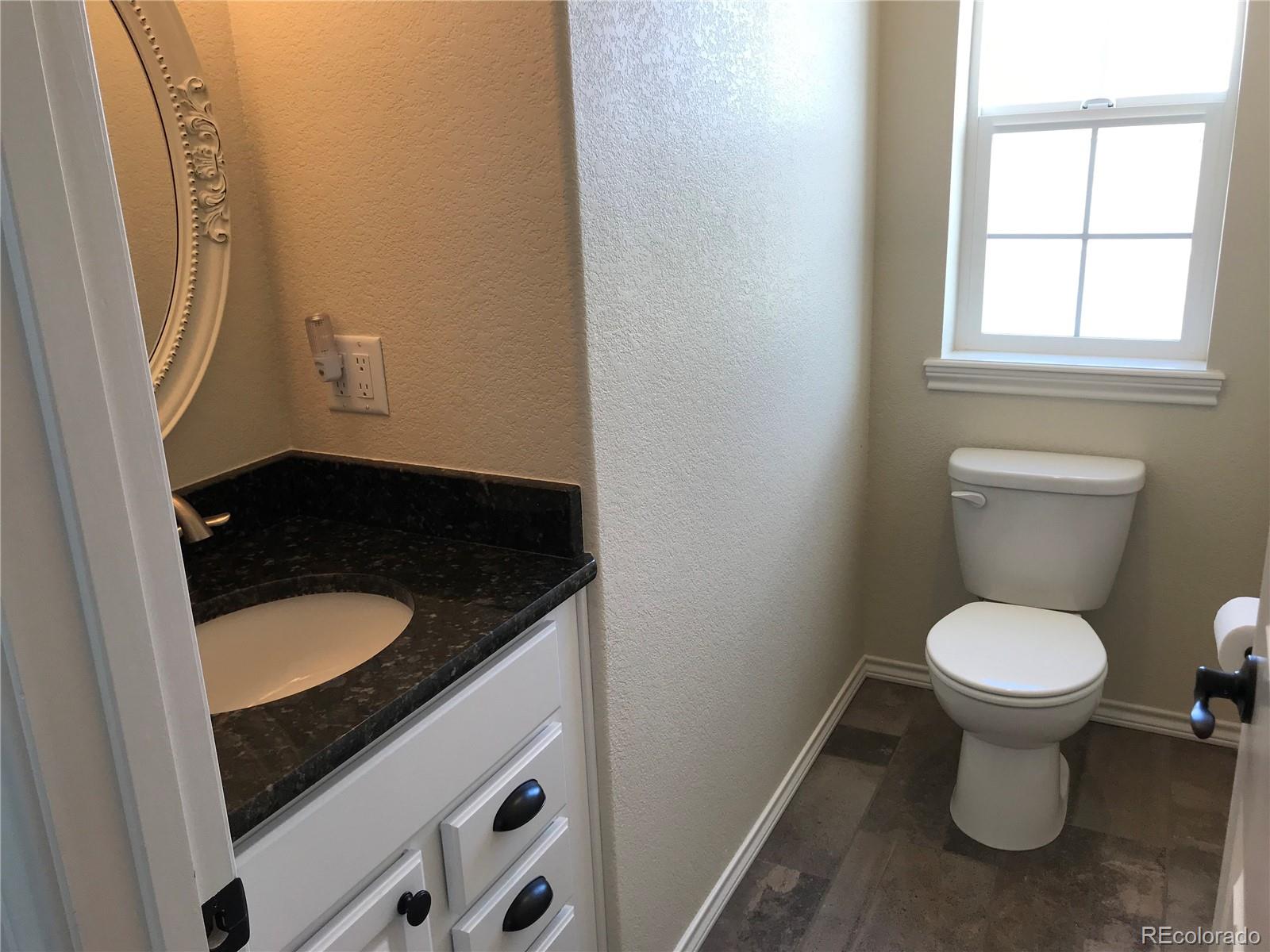 9345 North Log Road Calhan, CO 80808 - Photo 15 of 23 a bathroom with a granite countertop toilet and a sink