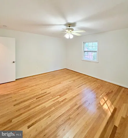 an empty room with wooden floor chandelier fan and windows