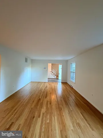 a view of empty room with window and wooden floor