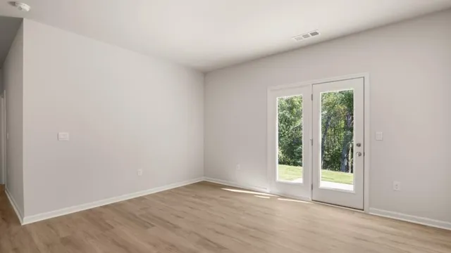 a view of an empty room with wooden floor and a window