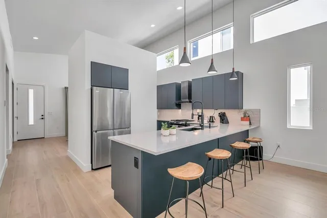 a kitchen with stainless steel appliances a refrigerator and a stove top oven with wooden floor