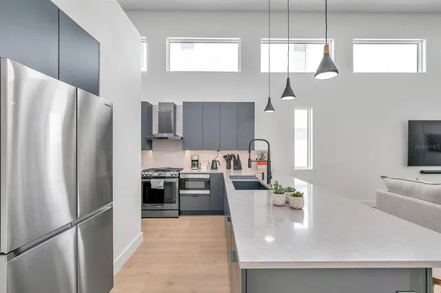 a kitchen with stainless steel appliances granite countertop a refrigerator a sink a stove and white cabinets