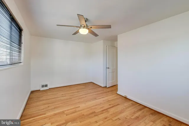 an empty room with wooden floor fan and windows