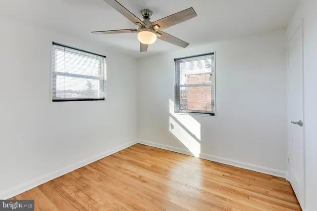 a view of empty room with wooden floor and fan