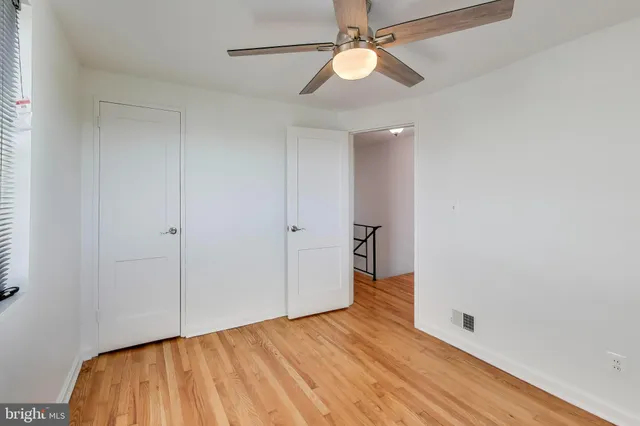 wooden floor in an empty room with a chandelier fan