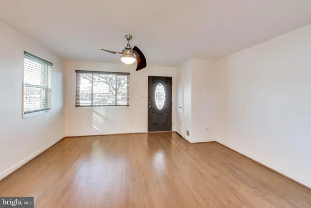 a view of an empty room with wooden floor and a window
