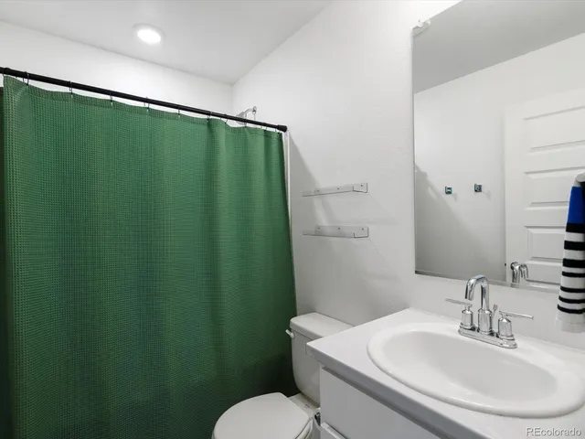 a bathroom with a granite countertop sink a toilet a large mirror and shower